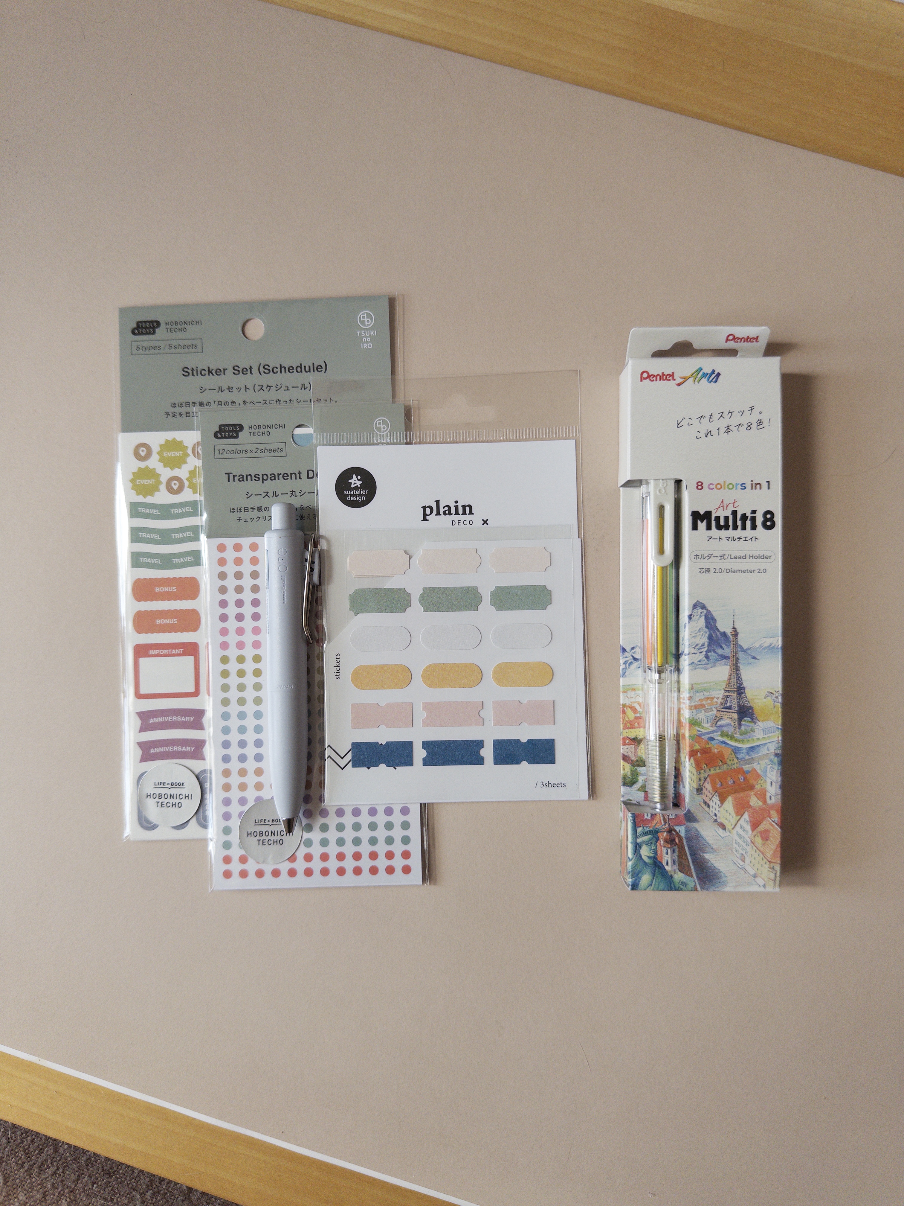 Sticker sets, a light blue Uniball One, and a Pental multi 8 colored pencil